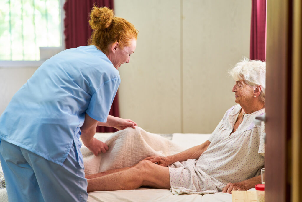 Nurse helping an eldery person out of bed